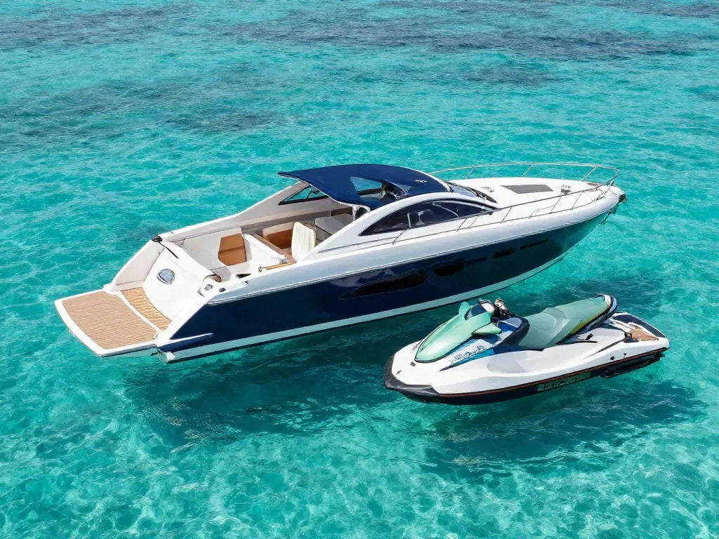 A navy tender and a jet ski floating in clear turquoise water beside a yacht